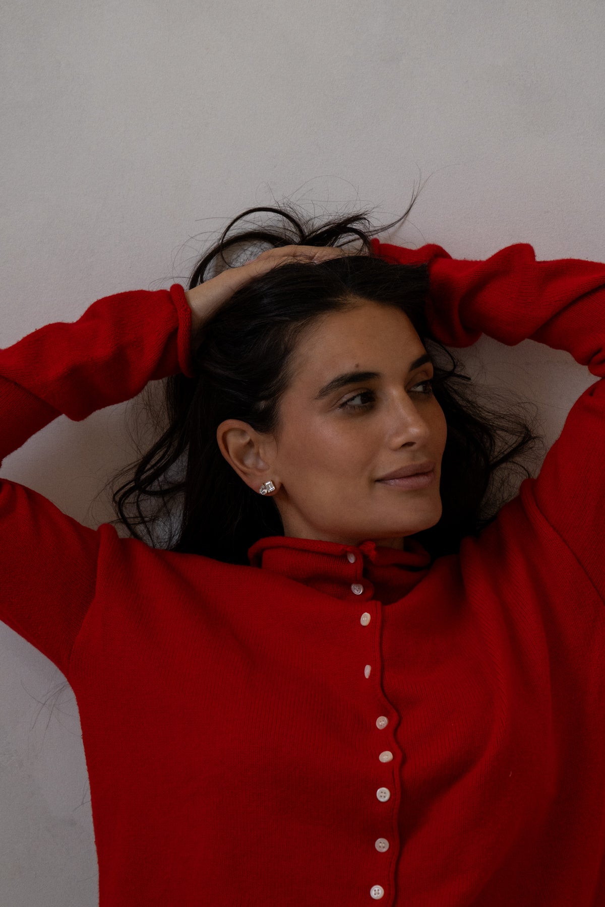 Model in a red sweater wearing sparkling earrings