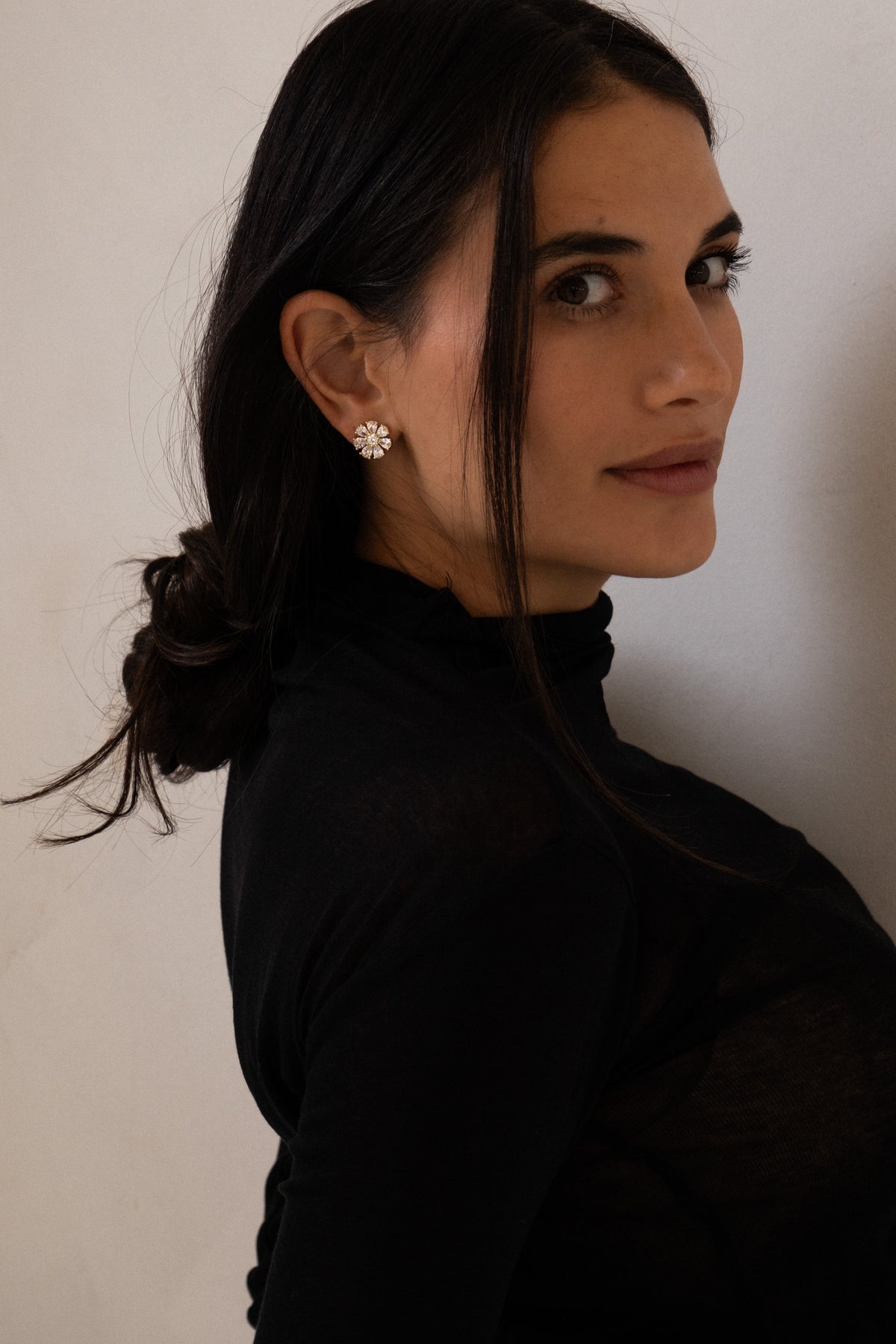 Maggie flower studs in gold worn with a black high-neck top